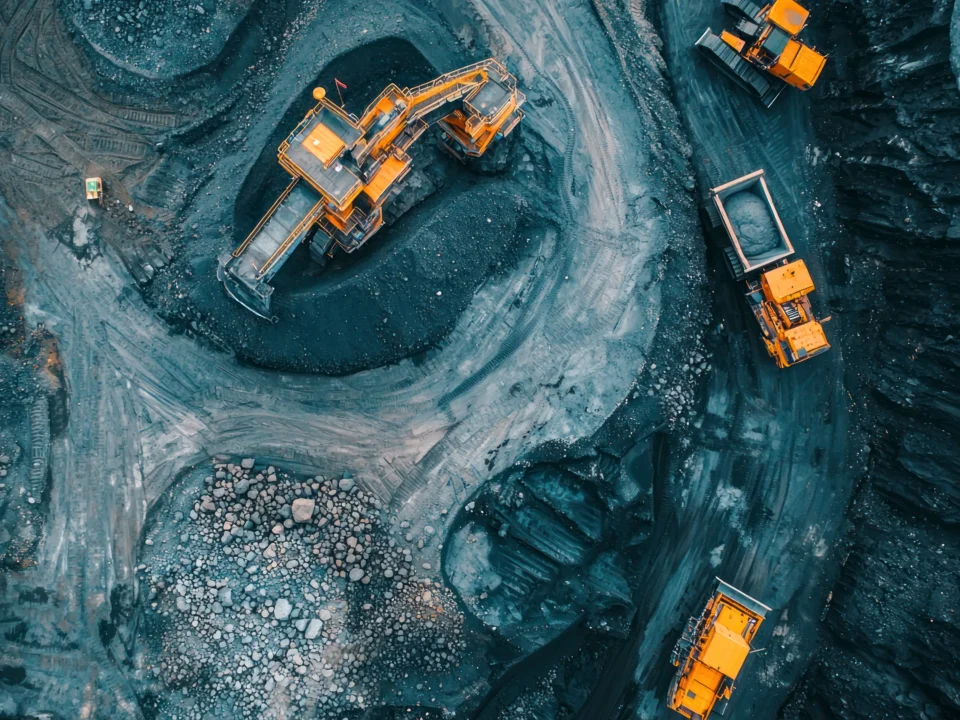Vista aérea de mineração a céu aberto com escavadeira e caminhões fora de estrada operando em área de extração de minério